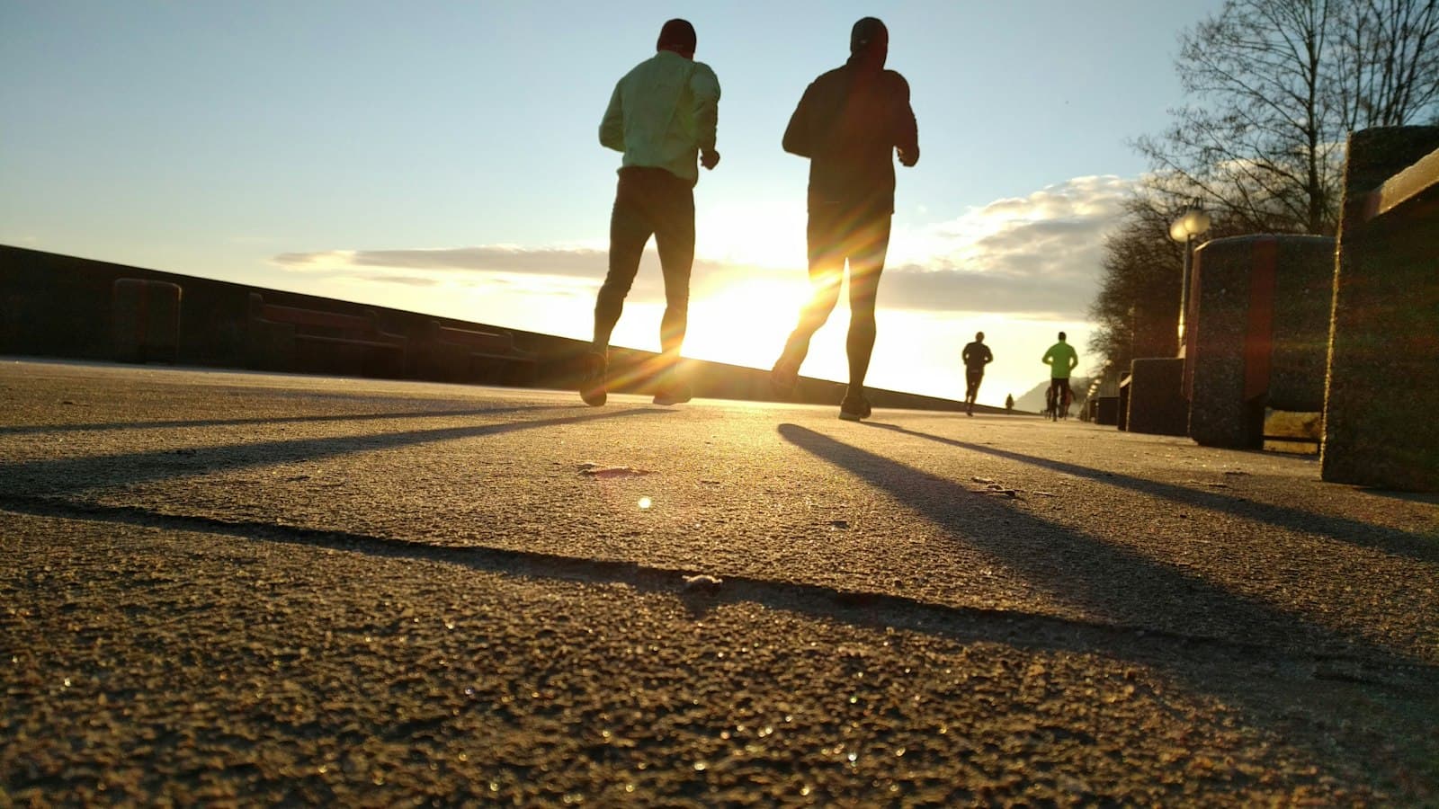 Two runners side by side on an embankment at sunset